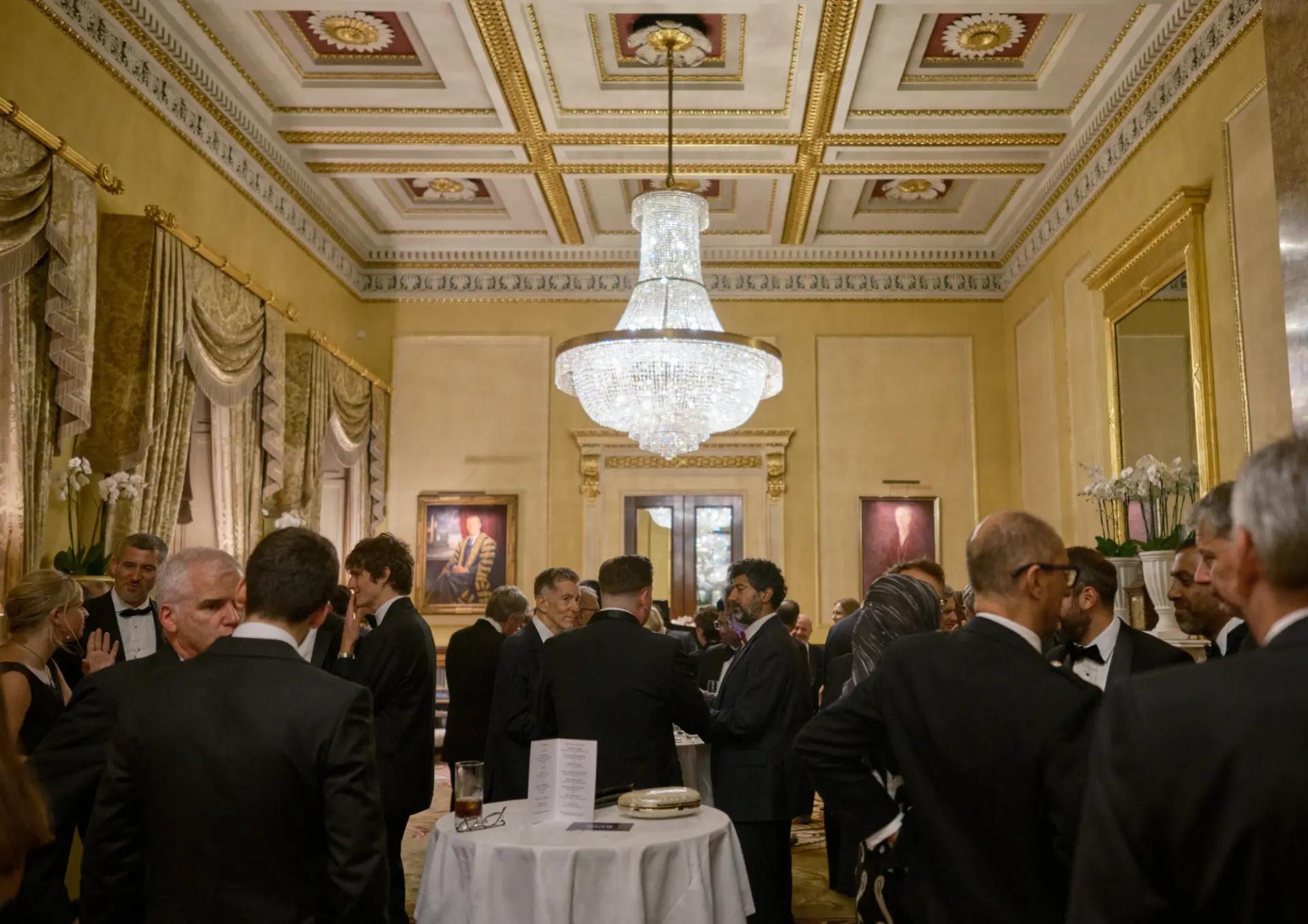 Guests mingling in the ballroom beneath the chandelier at The Room: Robotic Surgery